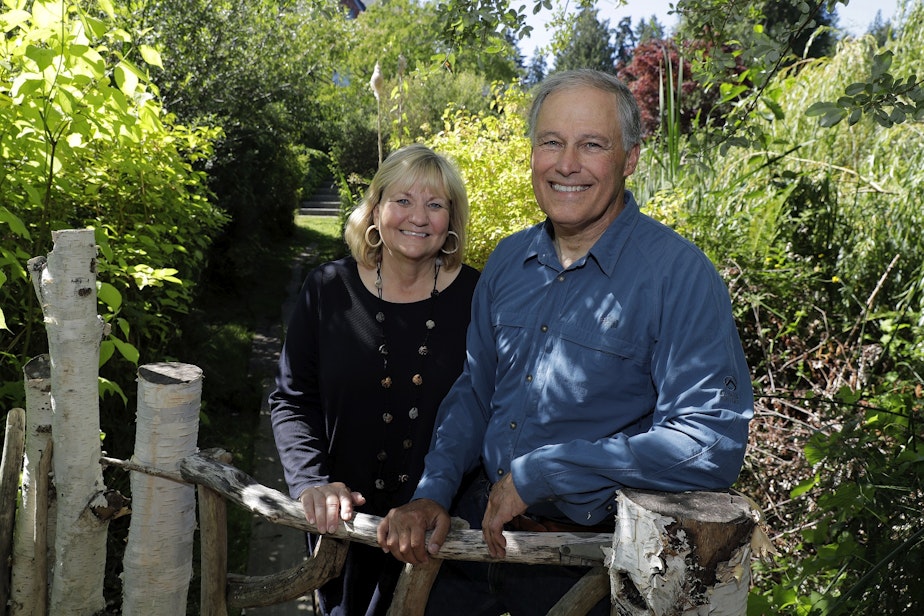 caption: In this July 23, 2018 photo, Washington Gov. Jay Inslee, poses for a photo with his wife Trudi Inslee, at their home on Bainbridge Island, Wash. 