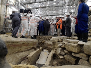 caption: France's Culture Minister Roselyne Bachelot (center left) visits the Notre Dame Cathedral archaeological research site in Paris on March 15 after the discovery of a 14th century lead sarcophagus.