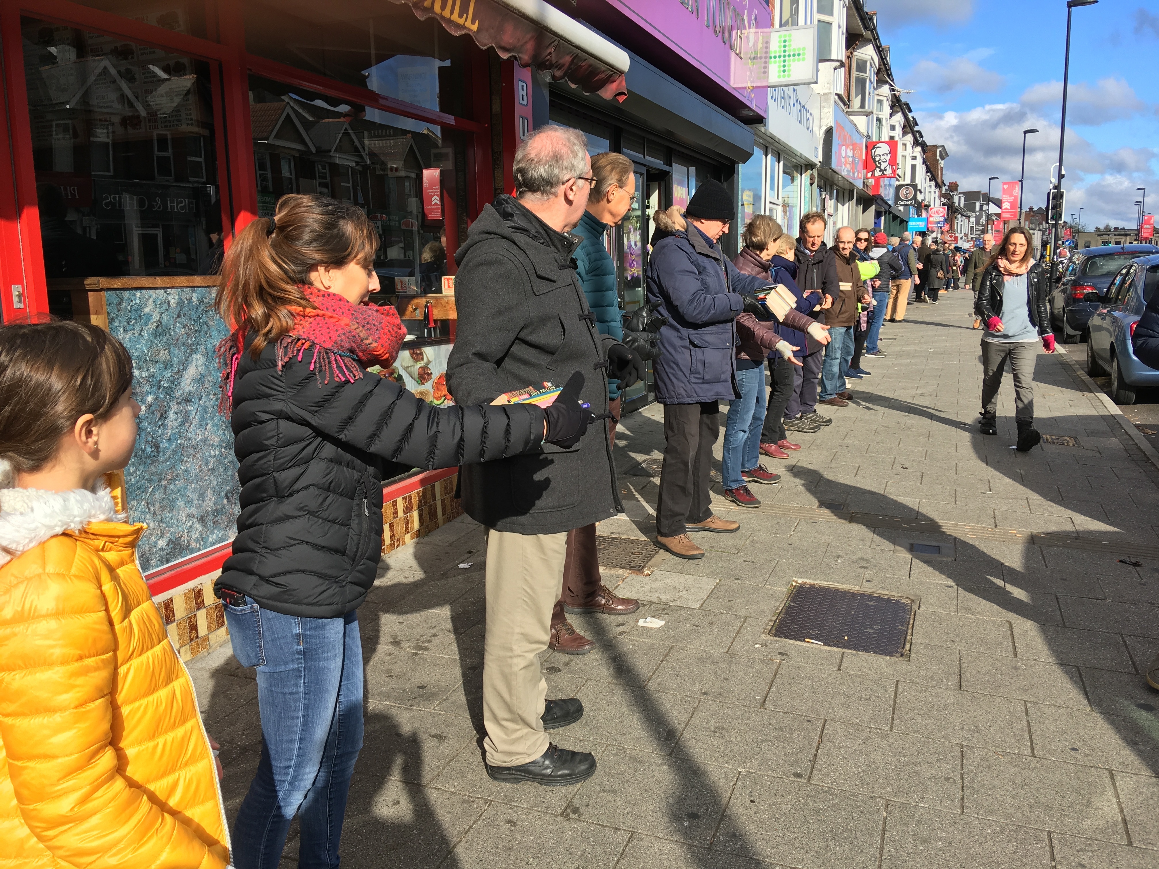 caption: People pass books down a chain to help the bookstore October Books move to a new location on Sunday in Southampton, England.