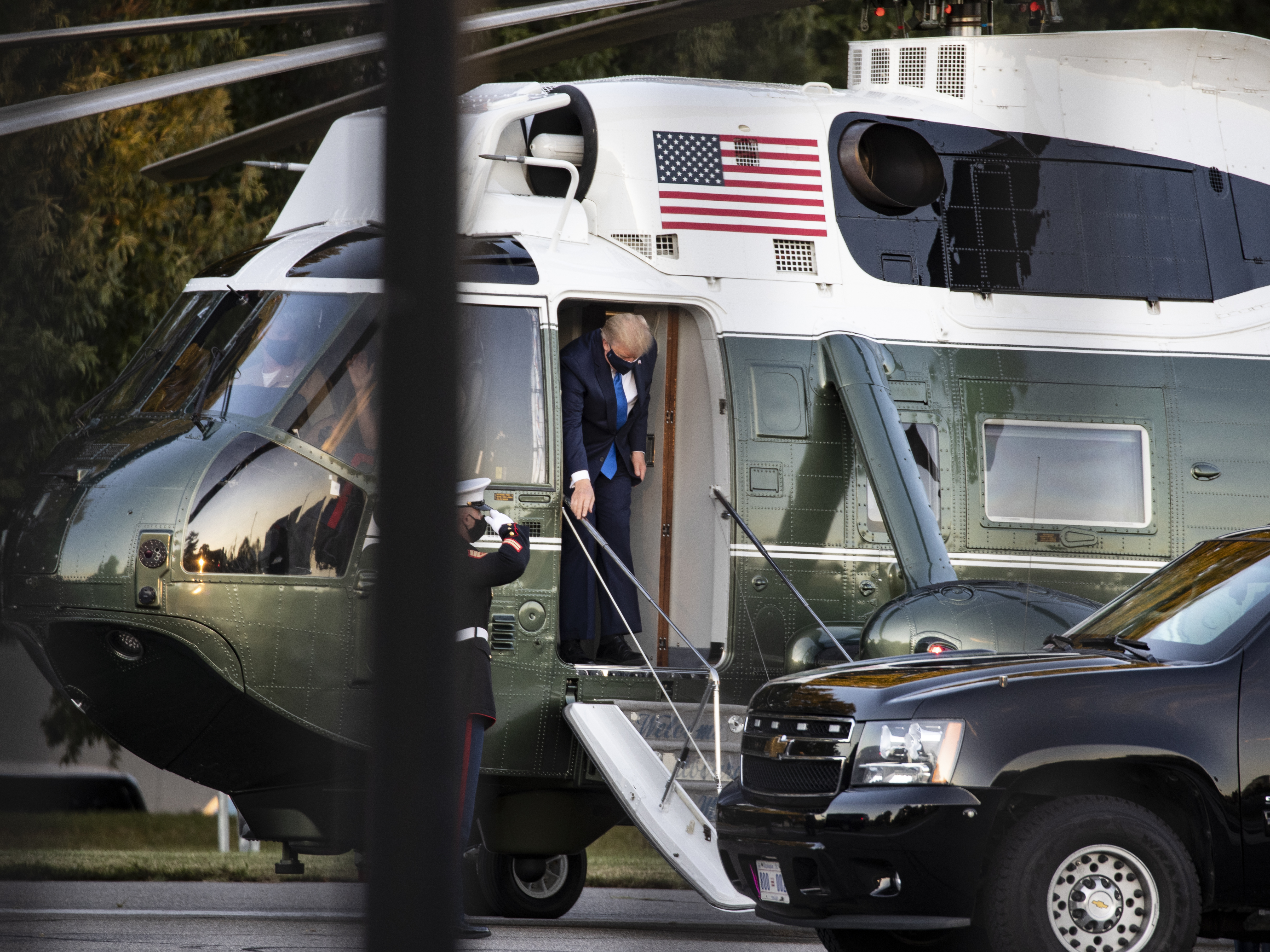 caption: President Trump exits Marine One at Walter Reed National Military Medical Center on Friday in Bethesda, Md. He is staying at the hospital while receiving treatment for the coronavirus.
