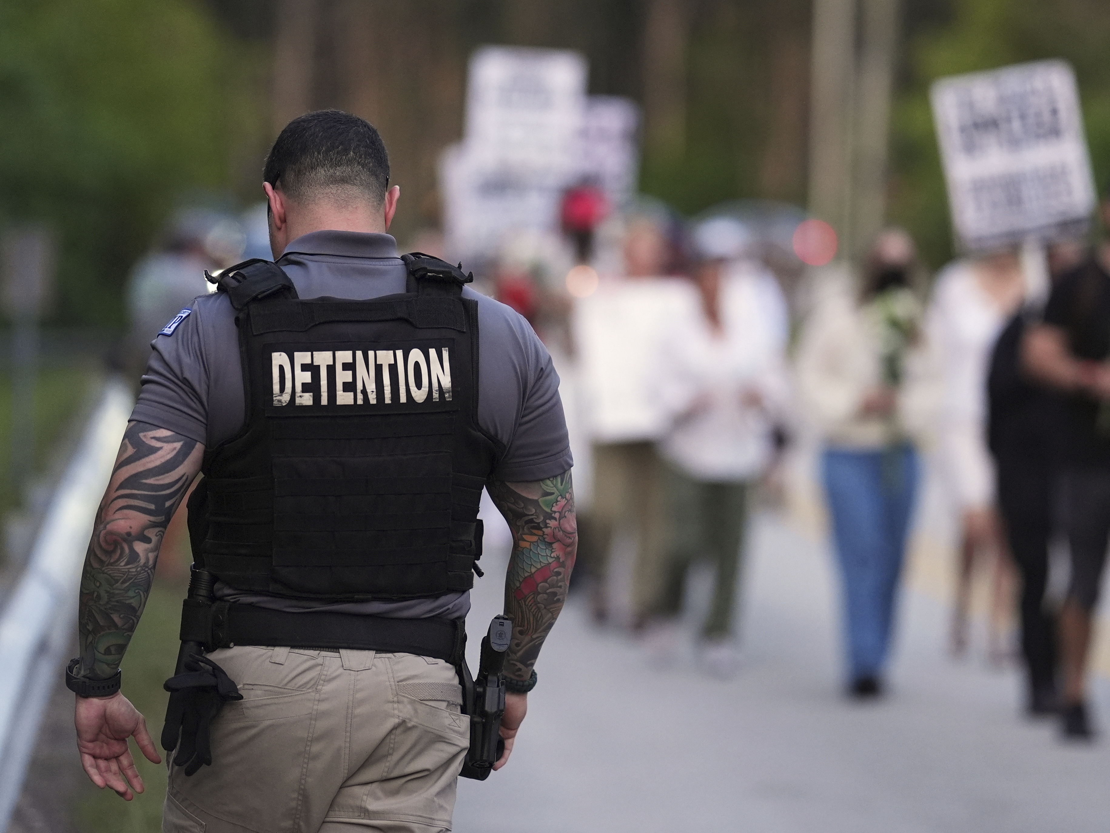 caption: A Krome Detention Center officer patrols as people hold a vigil on May 24 to recognize those who have died in U.S. Immigration and Customs Enforcement custody as well as those affected by mass deportations, outside Krome Detention Center in Miami.