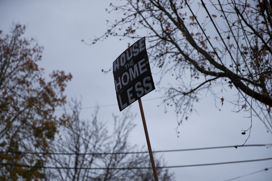 caption: A sign that reads 'house the homeless' is shown on Wednesday, December 16, 2020, near an encampment of unhoused community members at Cal Anderson Park in Seattle. 