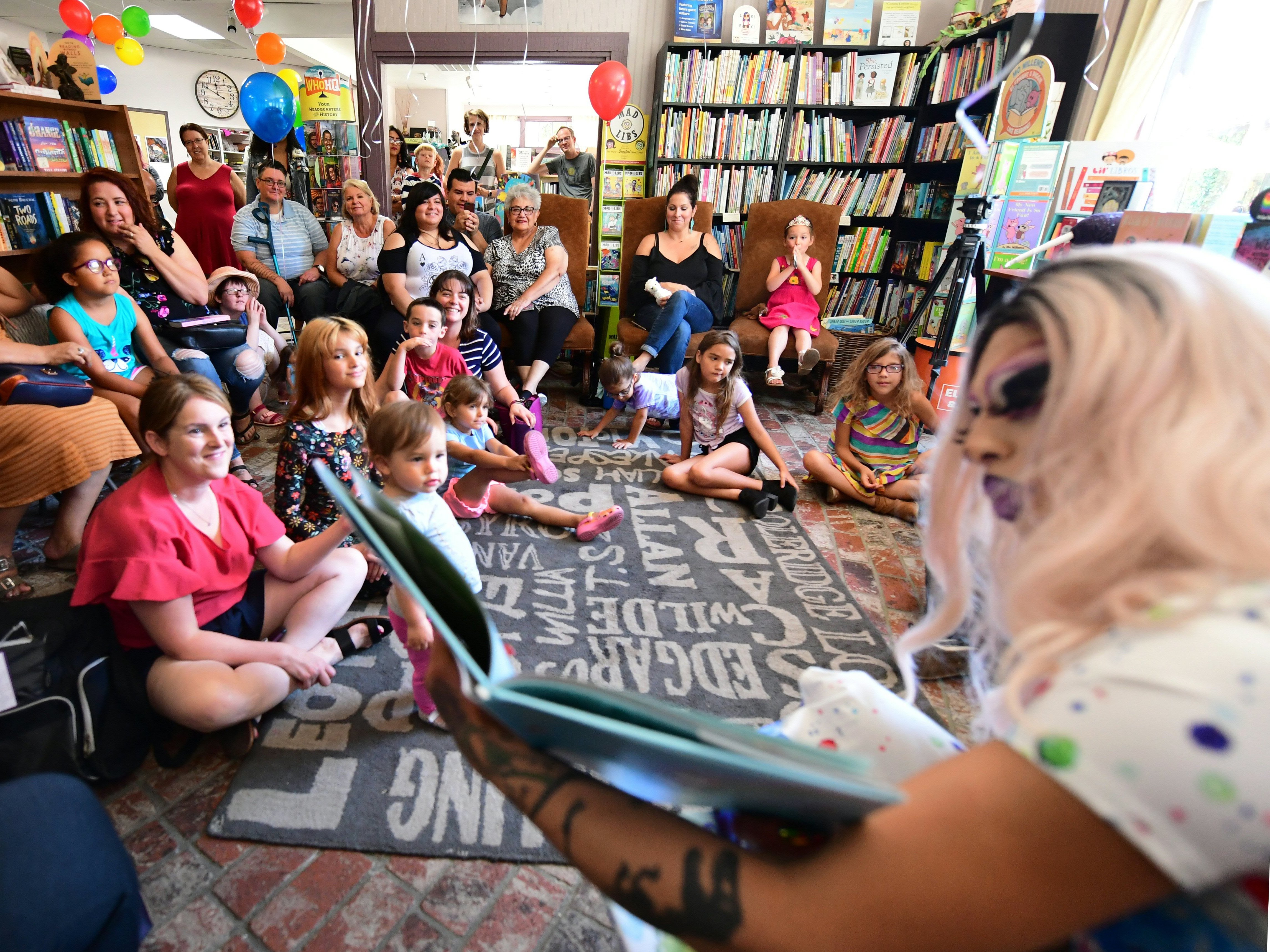 caption: Scalene Onixxx reads during Drag Queen Story Hour at Cellar Door Books in Riverside, Calif., in 2019