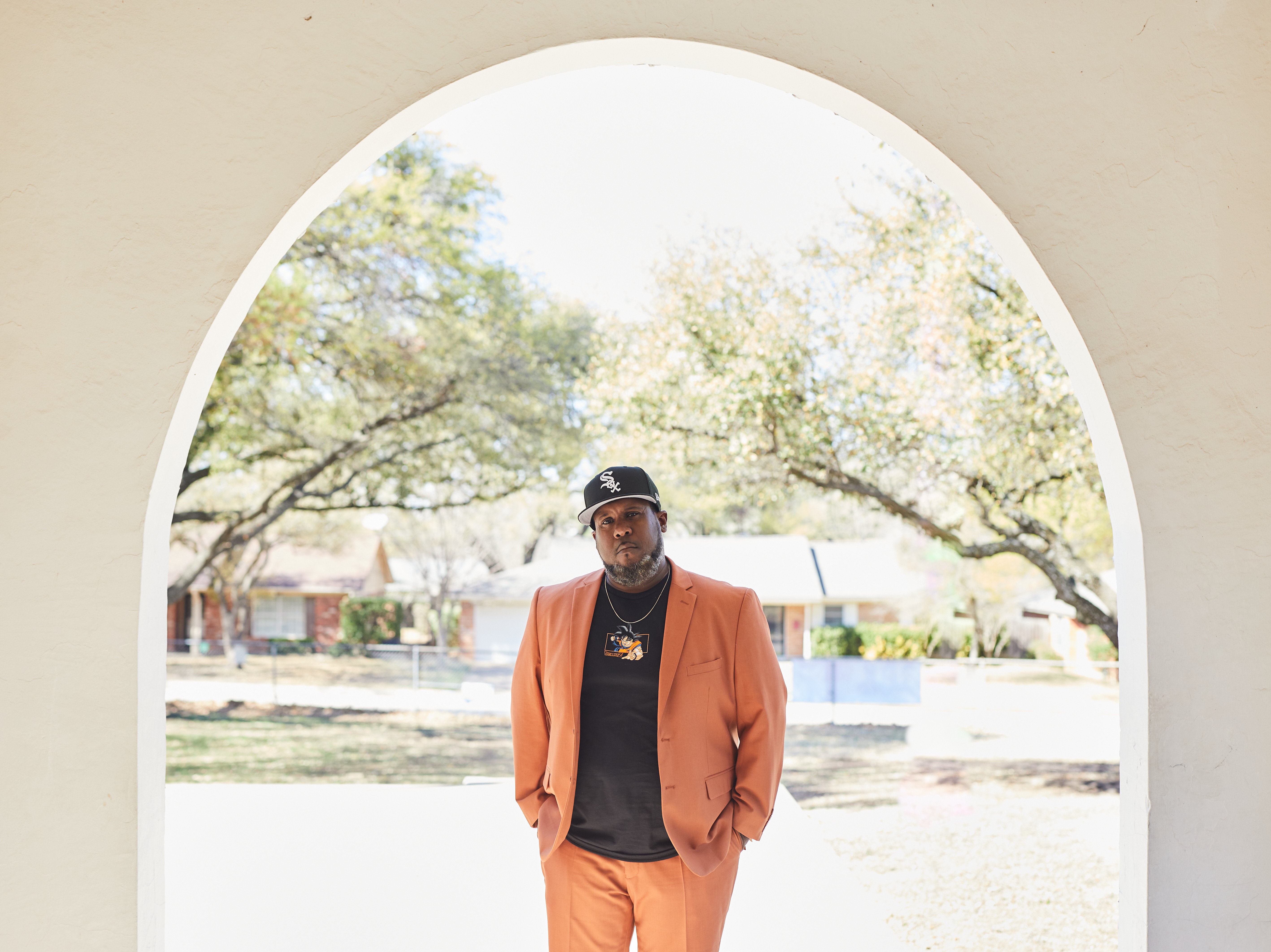 caption: Thomas Mayfield poses at the entrance of J. T. Stevens Elementary School.