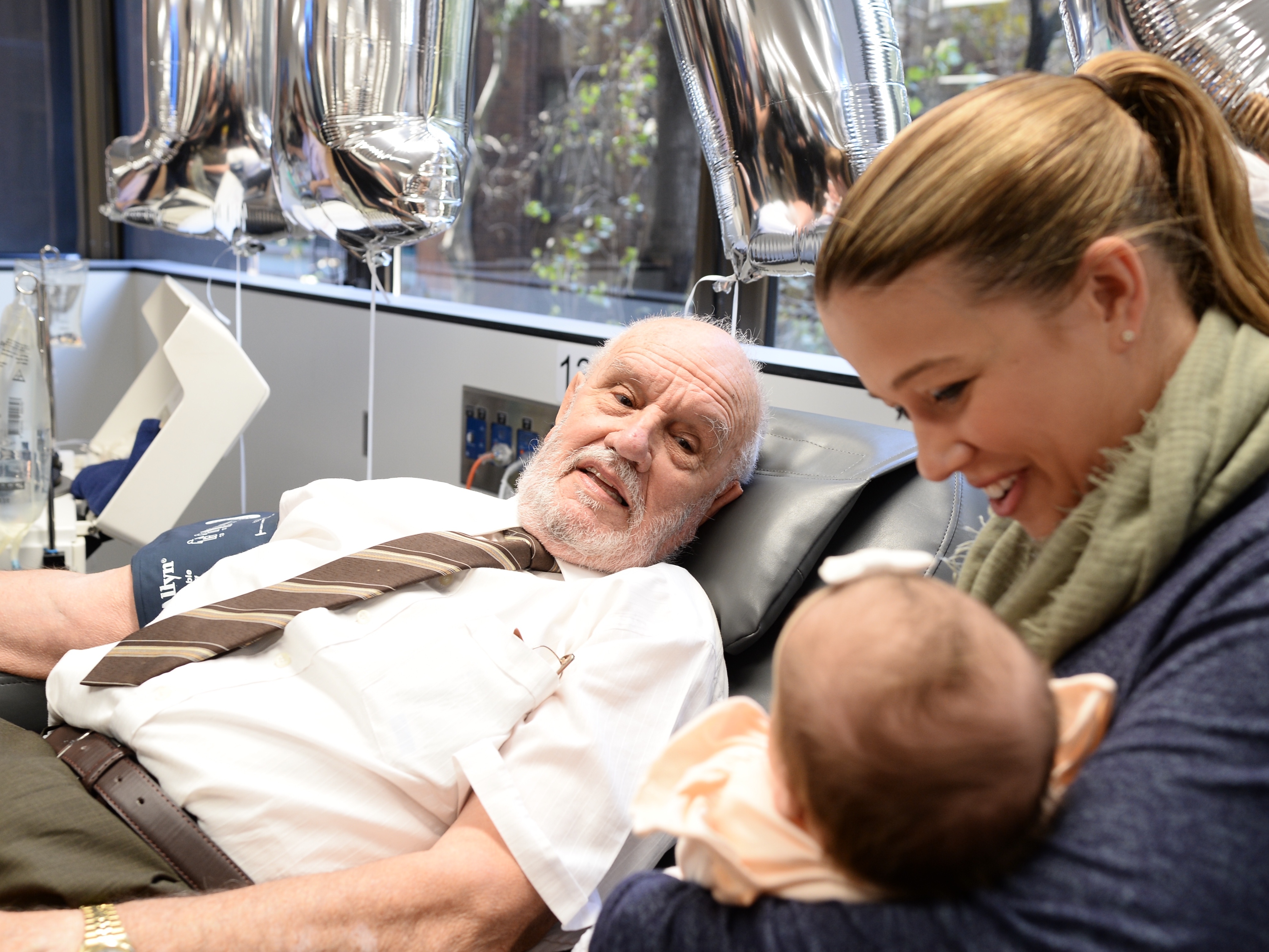 caption: James Harrison looks at 8-month-old Layla and her mother, Beth Ismay, in Sydney, Australia, in May 2018. It was the last time Harrison donated blood.