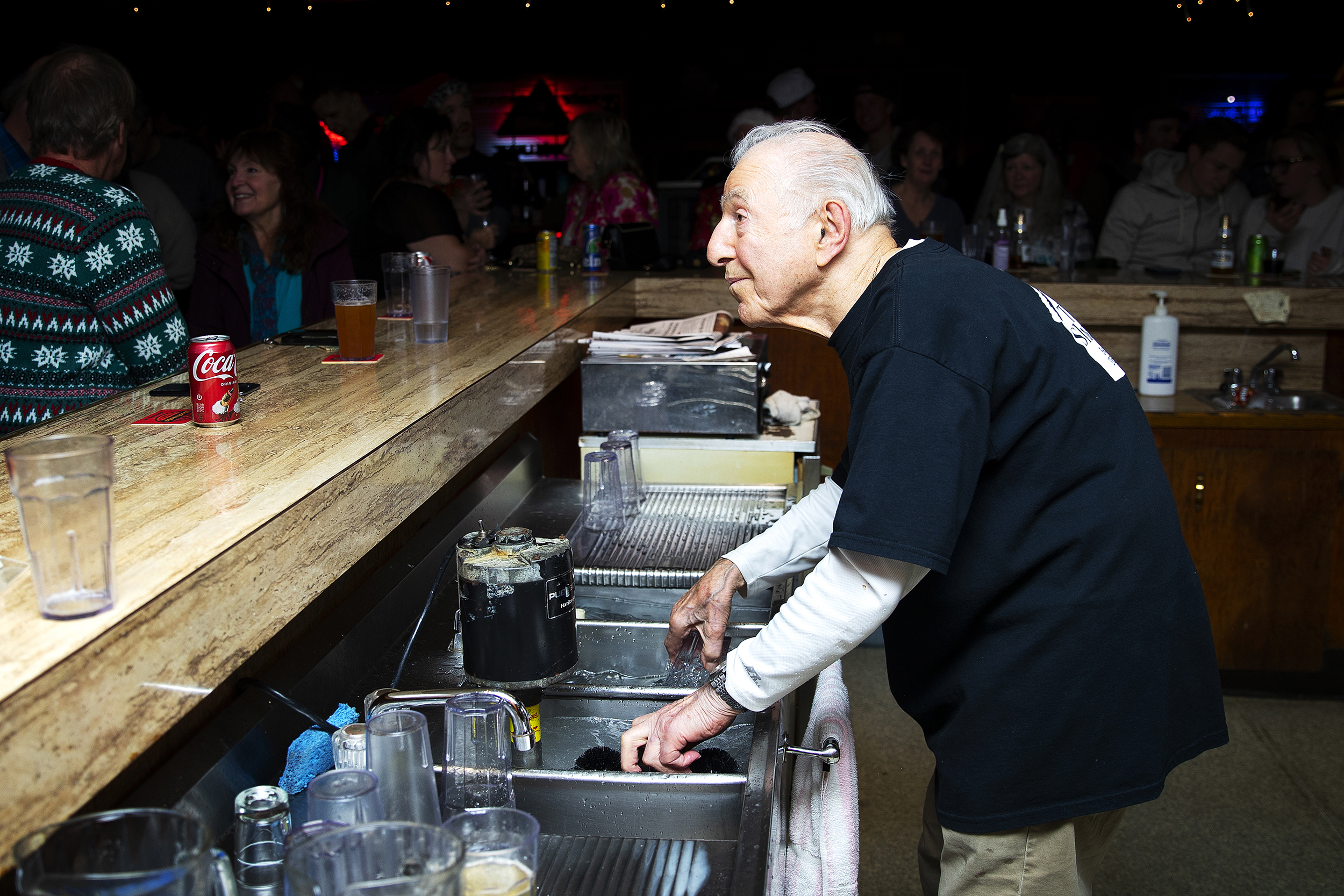 caption: John Spaccarotelli, 94-year-old owner and bartender at what many call the ‘last roadhouse in Seattle,’ tends bar on Friday, December 19, 2025, at the Shanty Tavern in Lake City. 