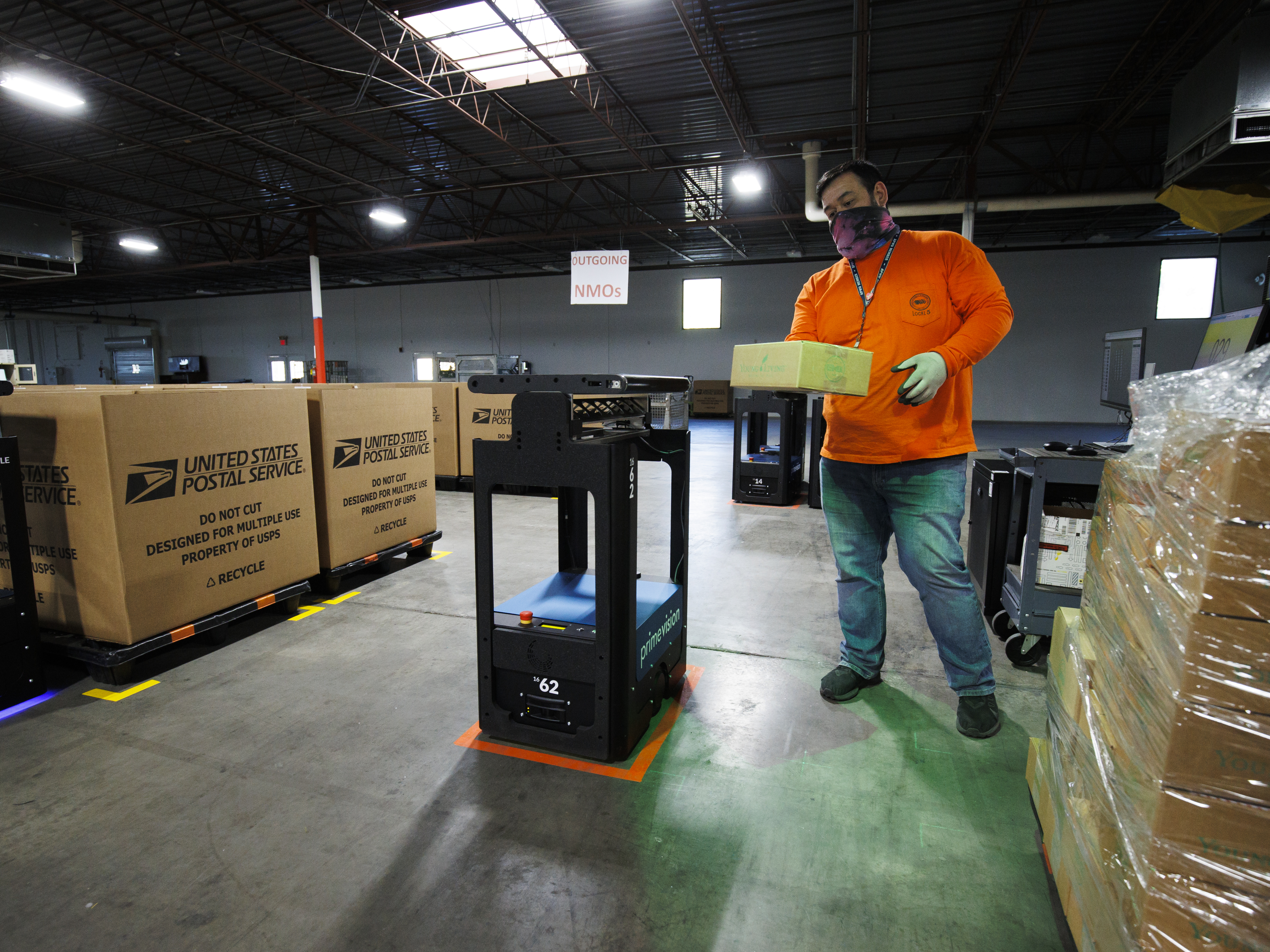 caption: One year after enduring an<em> </em>unprecedented backlog, the postal system is ready to handle mail and packages for the 2021 holiday season, Postmaster General Louis DeJoy said. Here, an employee loads a sorting robot during a media tour of a U.S. Postal Service package support annex in La Vergne, Tenn.