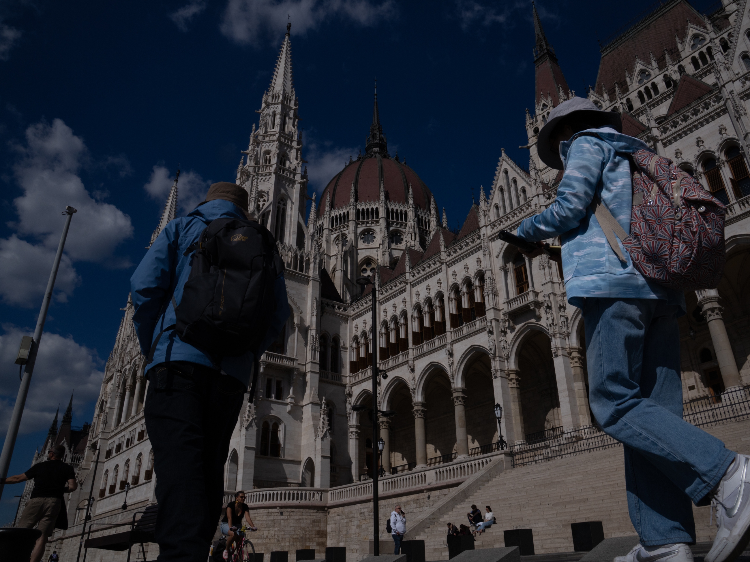 caption: People walk past Hungary's parliament building in Budapest in May.