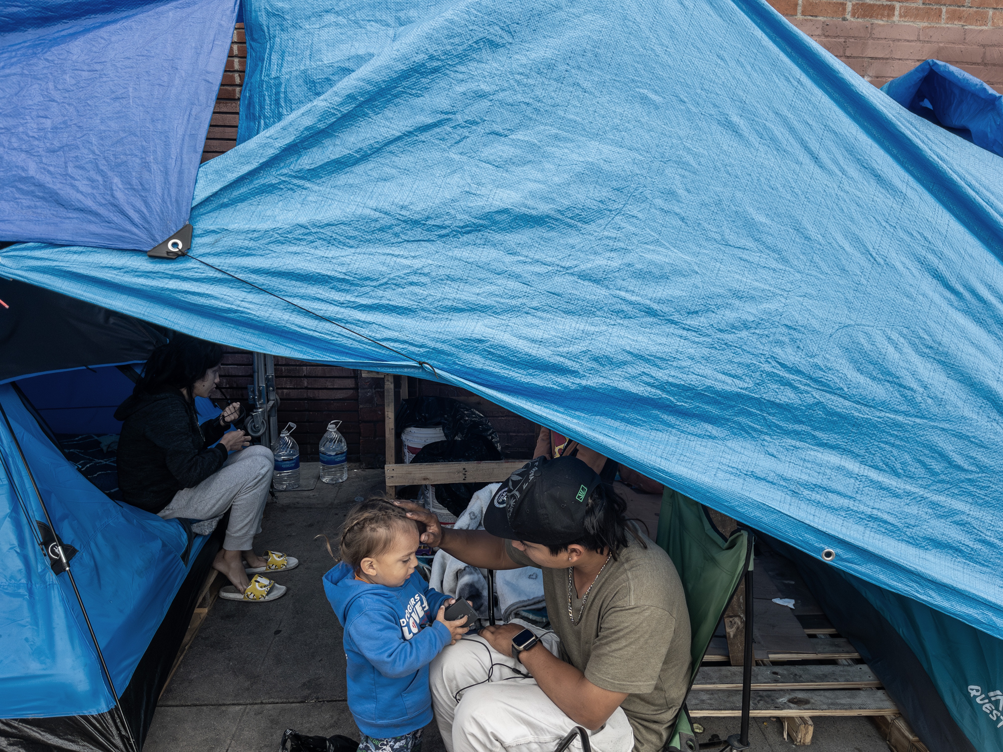 caption: A homeless family with a two-year-old child on Towne Avenue in Los Angeles' Skid Row in April 2024. A new study tracks how housing insecurity affects children's health over time. 