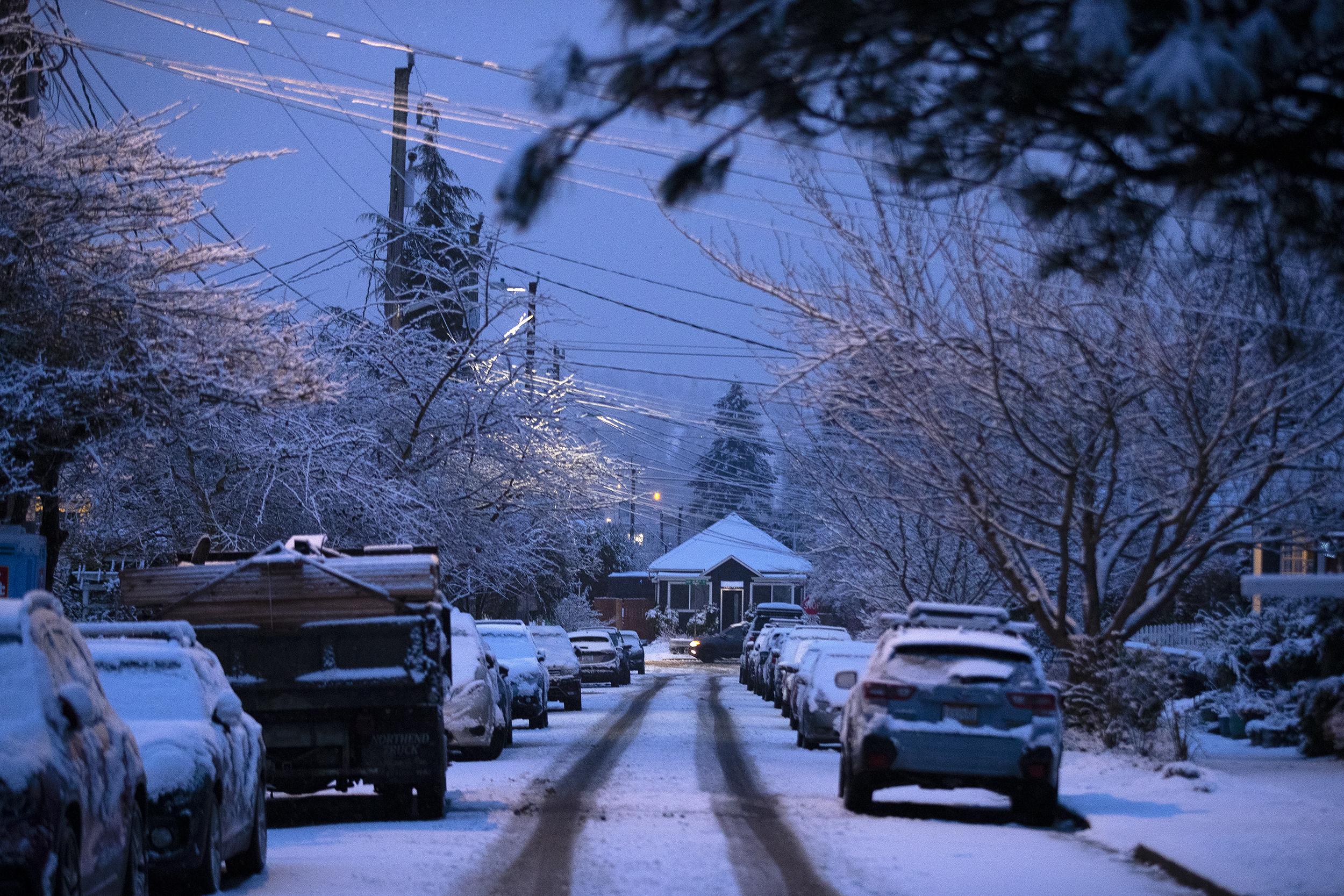 caption: Snow falls in the Ballard neighborhood as the sun rises on Thursday, February 6, 2025, in Seattle. 