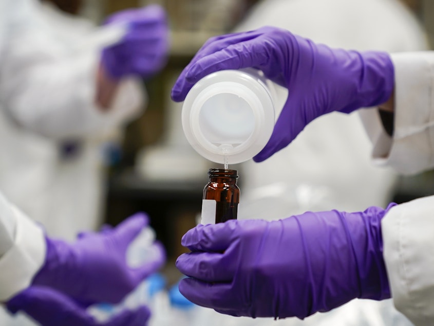 caption: Eva Stebel, water researcher, pours a water sample into a smaller glass container for experimentation as part of drinking water and PFAS research at the U.S. Environmental Protection Agency Center For Environmental Solutions and Emergency Response on Feb. 16, 2023, in Cincinnati.
