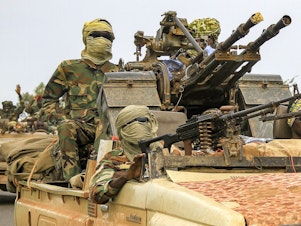 caption: Fighters ride in a vehicle moving in a military convoy accompanying the governor of Sudan's Darfur State on Aug. 30, 2023.