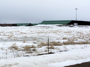 caption: This March 11, 2020 photo provided by the Bureau of Land Management shows a storage yard in Montana for pipe that was to be used in construction of the Keystone XL oil pipeline. The developer has now canceled the controversial project.