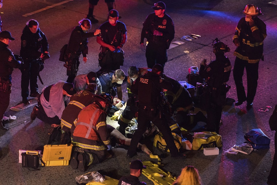 caption: Emergency workers tend to an injured person on the ground after a driver sped through a protest-related closure on the Interstate 5 freeway in Seattle, authorities said early Saturday, July 4, 2020. 