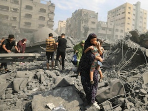 caption: Palestinians evacuate the area following an Israeli airstrike on the Sousi mosque in Gaza City on October 9, 2023.