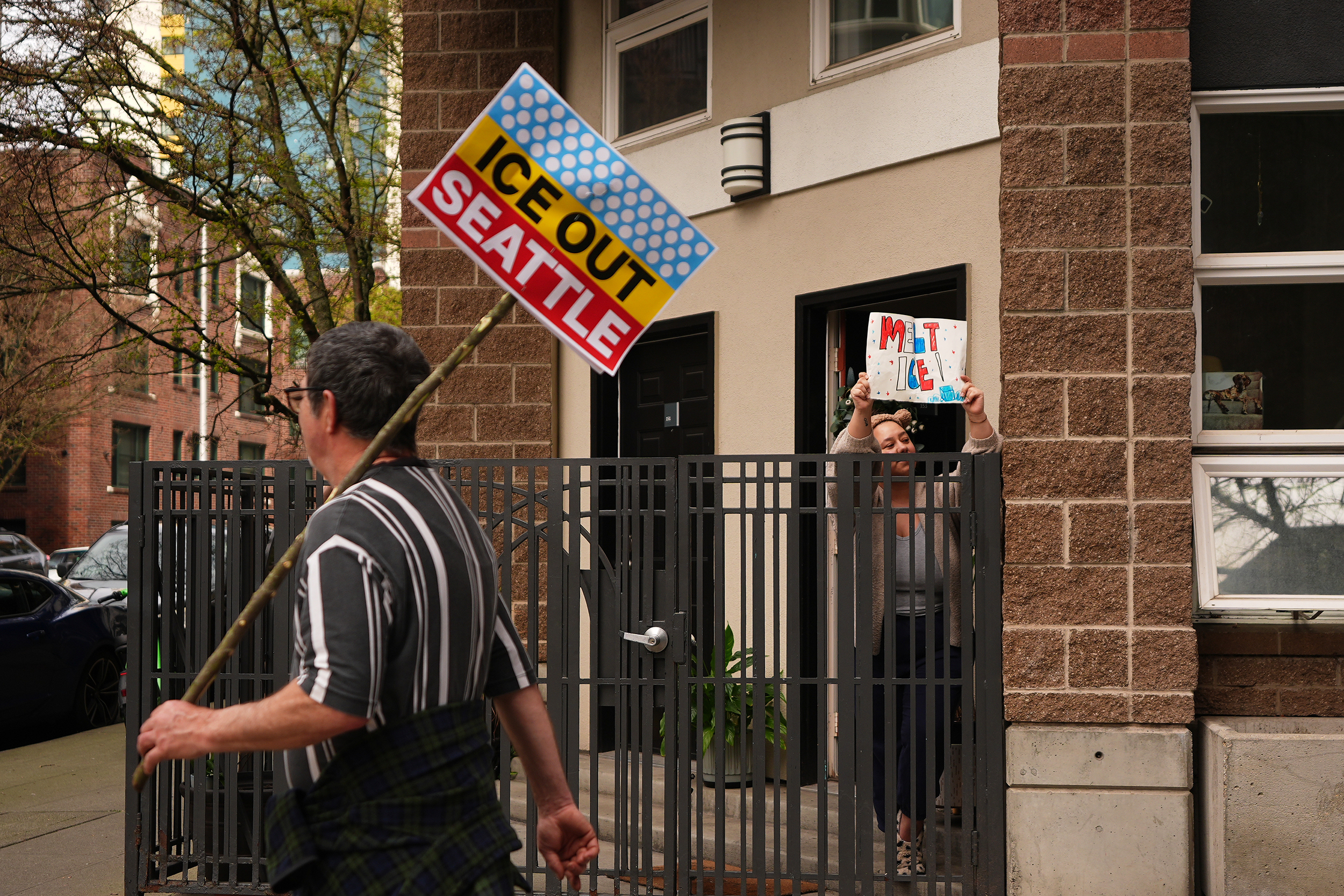 caption: A resident waves a "melt ICE" sign from their doorstep as a "No Kings" protest march passes by, Saturday, March 28, 2026, in Seattle. 