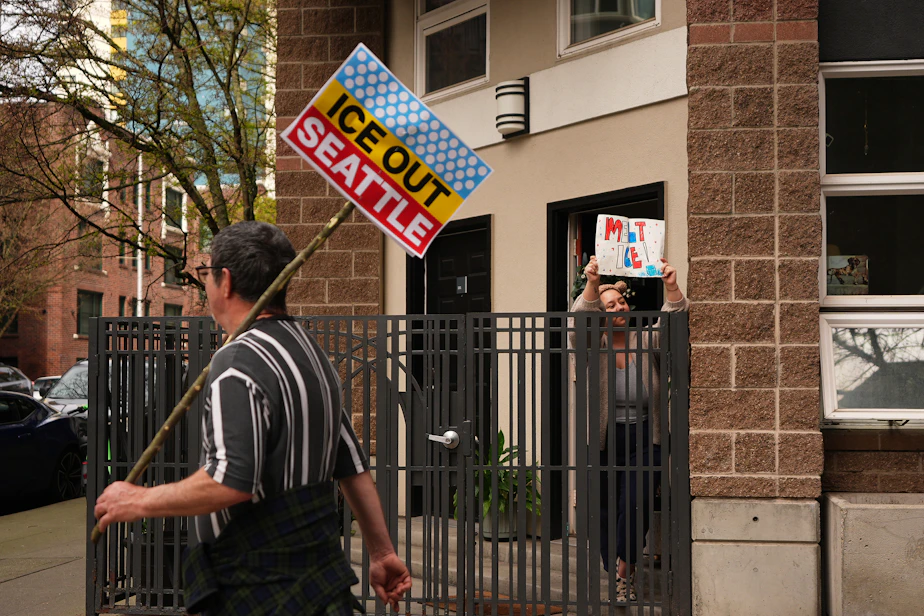 caption: A resident waves a "melt ICE" sign from their doorstep as a "No Kings" protest march passes by, Saturday, March 28, 2026, in Seattle.