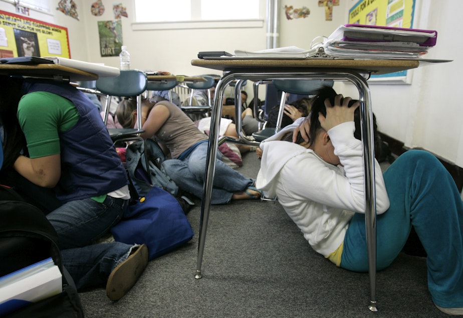 caption: Ninth-grade students, including Mahlia Butler, 15, right, take part in a statewide earthquake drill, Tuesday, April 24, 2007, as they "drop, cover, and hold" under their desks at King's High School, a private school near Seattle in Shoreline, Washington.