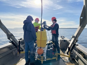 caption: SMRU science consultants and Gravity Marine staff attach an acoustic release to the hydrophone in Useless Bay. The hydrophone collects data on the intensity of noise pollution.
