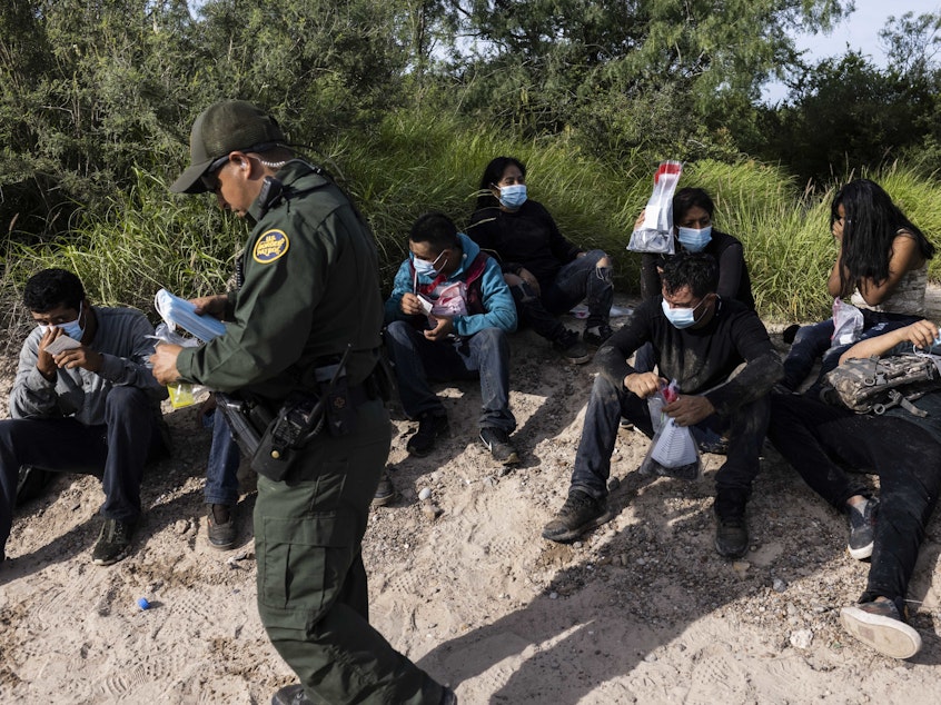 caption: Migrants are apprehended by U.S. Customs and Border Protection agents in LaJoya, Texas in June.