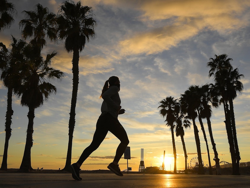 caption: A jogger runs on Santa Monica State Beach on April 10 in Santa Monica, Calif. Running is one form of exercise that meets social distancing guidelines.