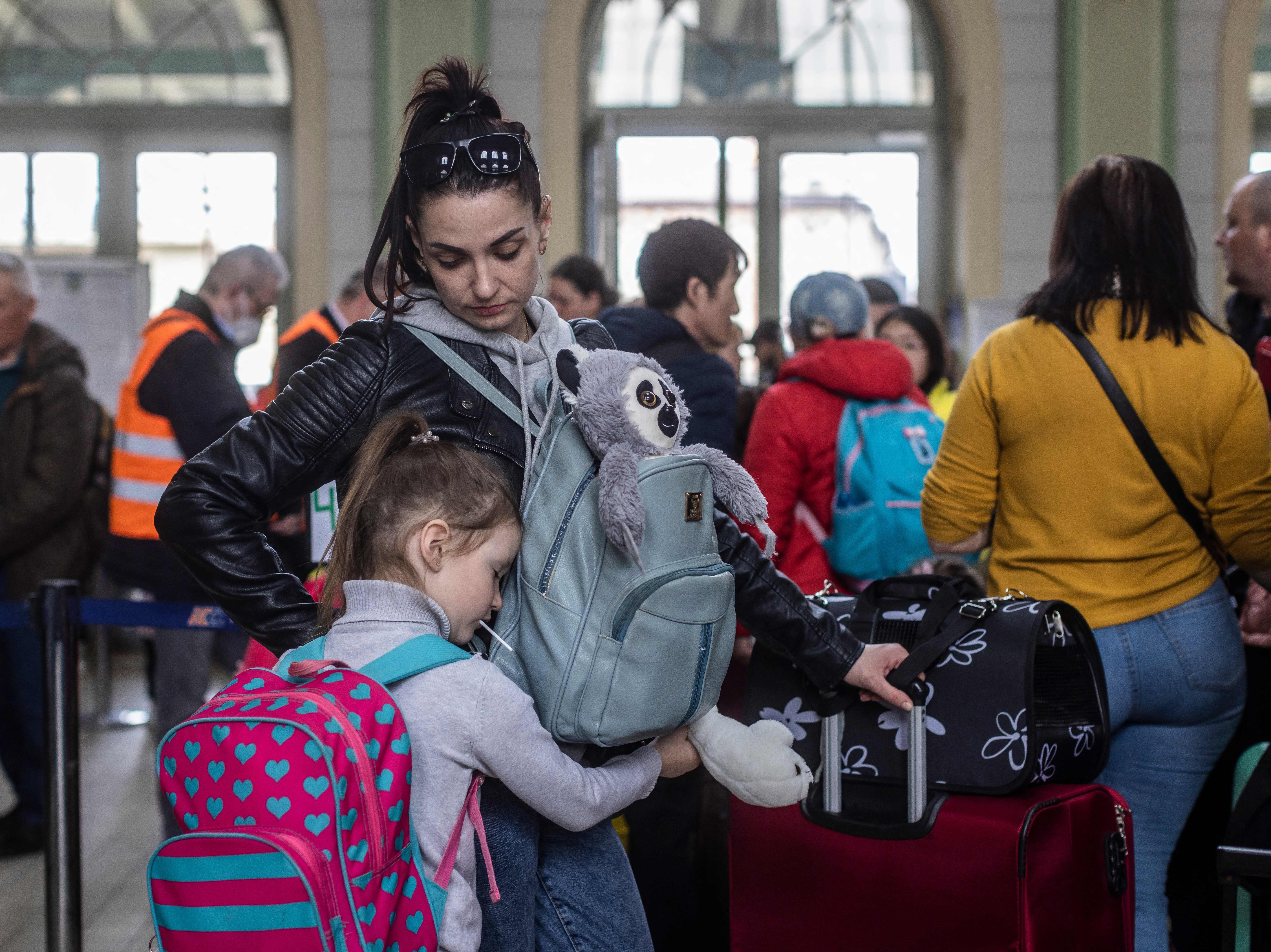 caption: A woman and a child, along with other refugees from Ukraine, wait in the ticket hall of the railway station in Przemysl in eastern Poland.