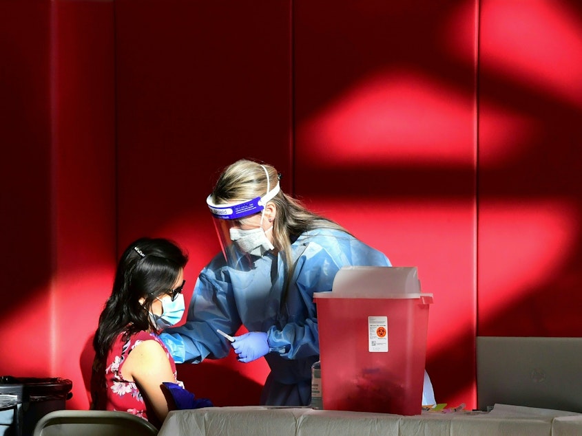 caption: A registered nurse administers the COVID-19 vaccine at a high school gym in Corona, California. Scientists are trying to determine if vaccines (and boosters) will offer protection against the newly identified omicron variant.