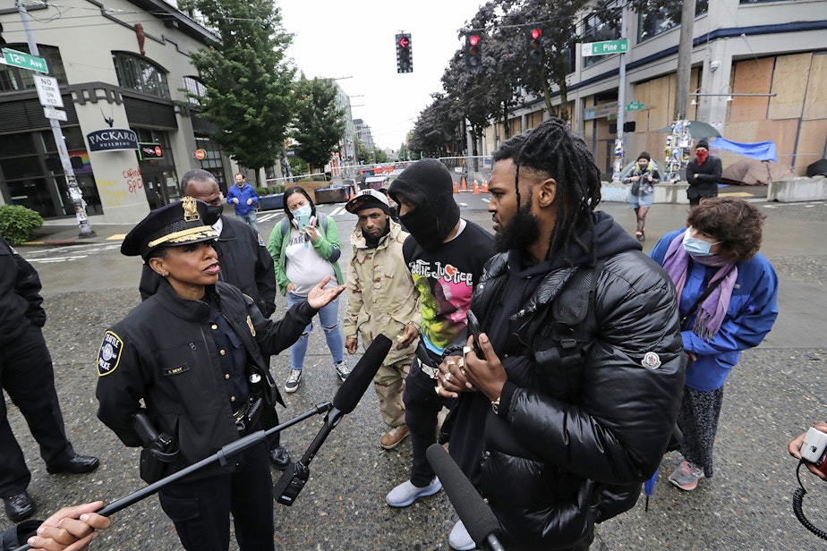 caption: Raz Simone, right front, and other activists speak with Seattle Police Chief Carmen Best, left, near a plywood-covered and closed Seattle police precinct behind them Tuesday, June 9, 2020, in Seattle, following protests over the death of George Floyd, a black man who was in police custody in Minneapolis.