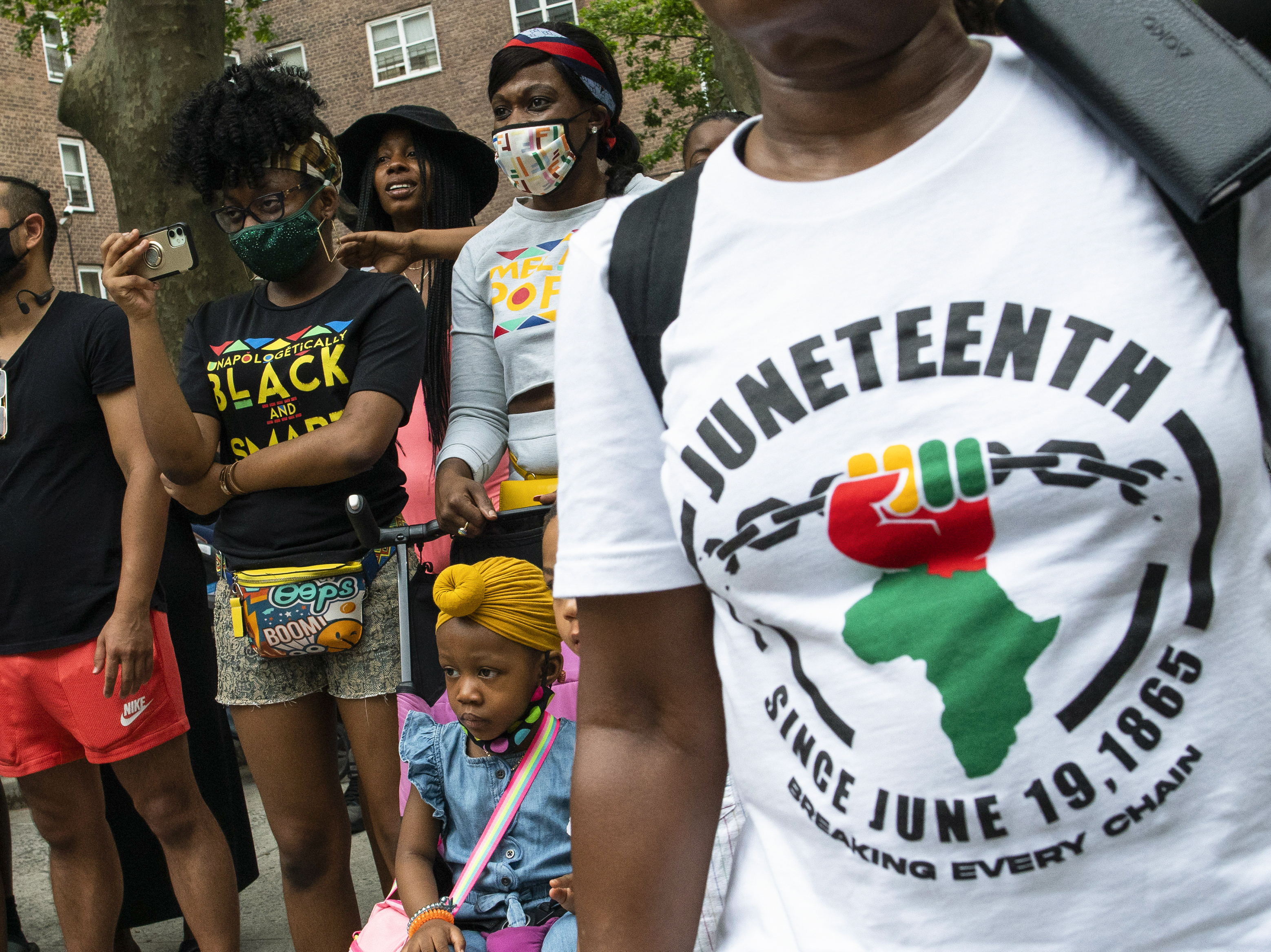 caption: People attend Juneteenth celebrations in the Harlem neighborhood of New York, on June 19, 2021.