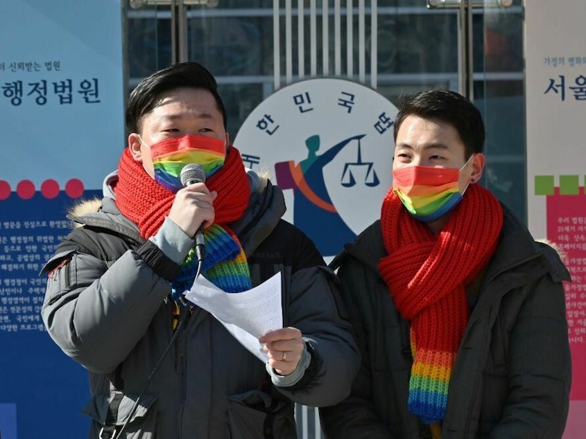 caption: So Seong-uk, left, speaks at a press conference while his partner Kim Yong-min looks on in February 2021 as they file a lawsuit against South Korea's National Health Insurance Service at the Seoul Administrative Court.