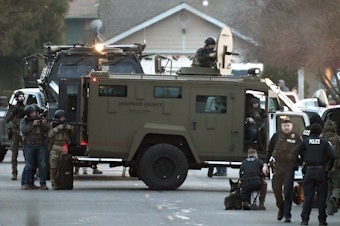 caption: Law enforcement officers aim their weapons at a home during a standoff in Grants Pass, Ore., on Tuesday, Jan. 31, 2023. Police said the standoff involving a man suspected in a violent kidnapping in Oregon who was barricaded underneath the home had been "resolved."