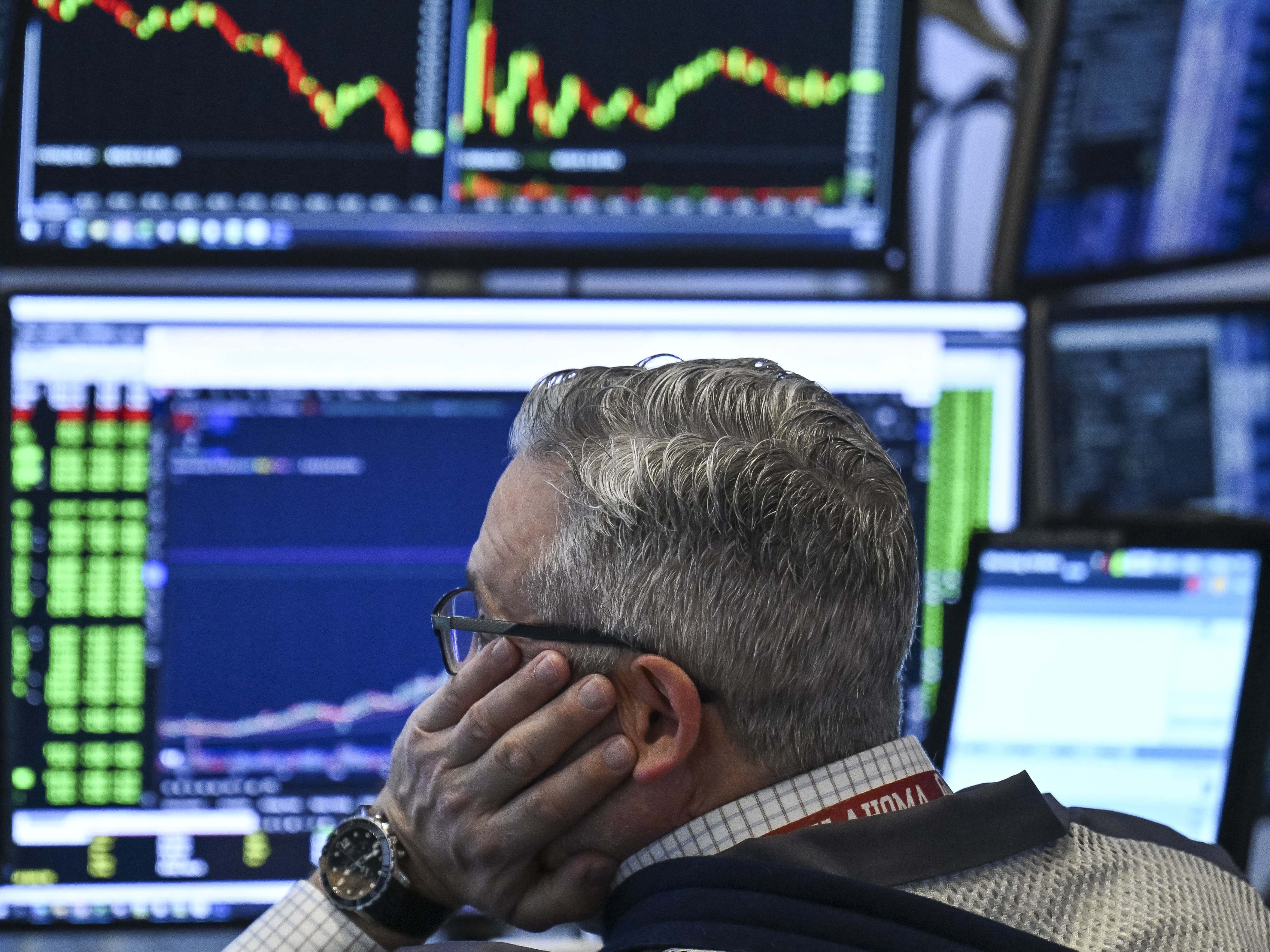 caption: A trader works on the floor of the New York Stock Exchange (NYSE) at the opening bell on Tuesday. Stocks were modestly higher on Wednesday, although investors remained on edge after four days of heavy losses.