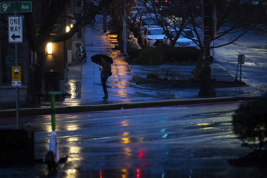 caption: A pedestrian waits on the corner of 9th Avenue and Westlake Avenue with an umbrella in the early morning hours of Tuesday, February 25, 2025, in Seattle.