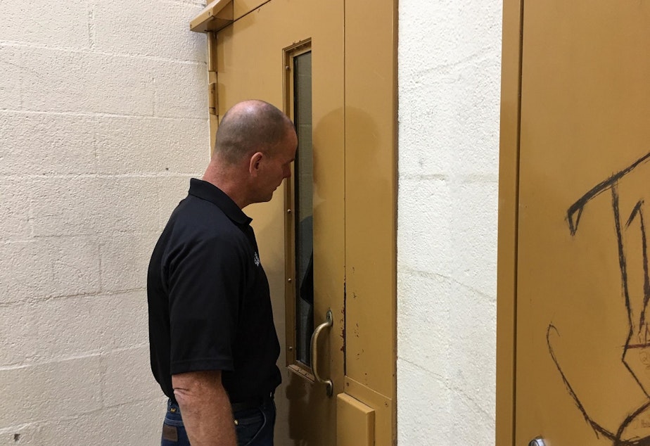 caption: Mason County Jail Director Kevin Hanson speaks to an inmate who is triple-bunked in a cell originally built for one.