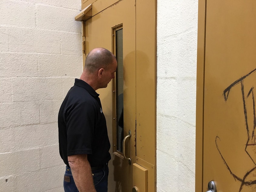 caption: Mason County Jail Director Kevin Hanson speaks to an inmate who is triple-bunked in a cell originally built for one.