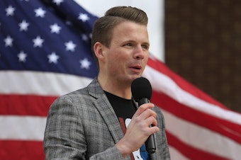 caption: Ryan Fournier, pictured here speaking at a rally in Sugar Hill, Georgia in 2021, has been charged with assaulting a woman with a firearm.