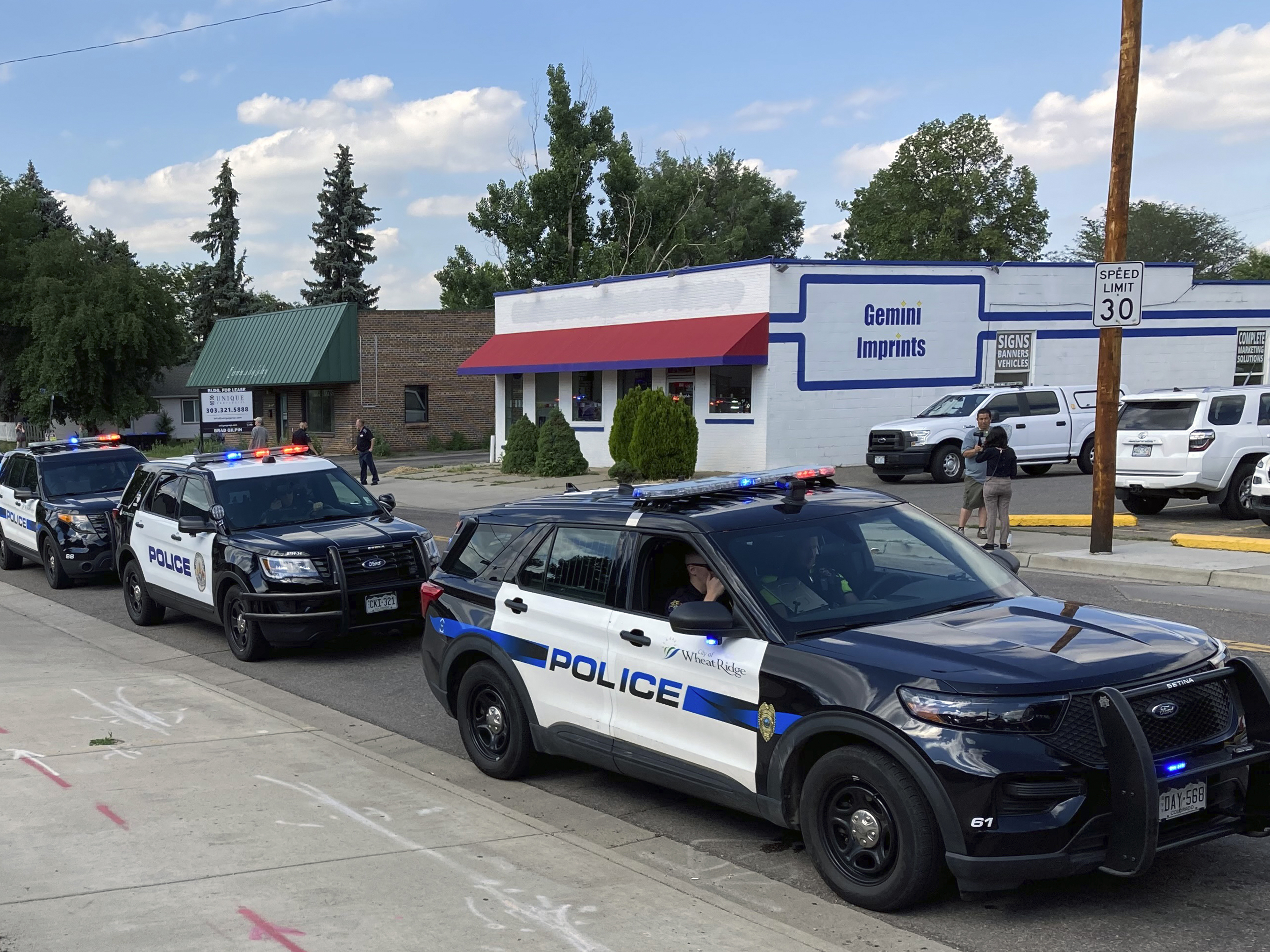 caption: About 30 police cars line up for a procession in honor of an officer who was fatally shot in Arvada, Colo., Monday, June 21.