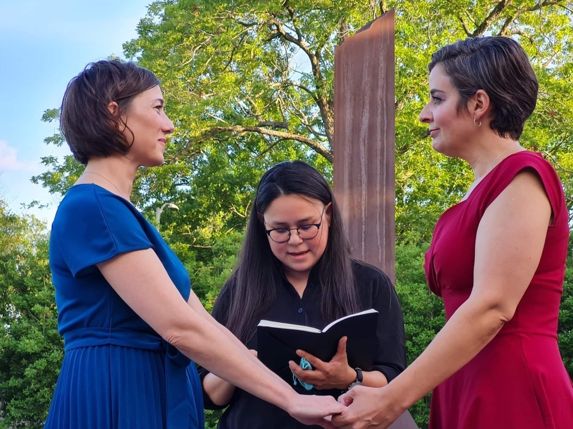 caption: Carlie Brown (left) and Molly Pela exchange wedding vows as their friend, Julie Takahashi, officiates the ceremony. Both women said they rushed to get married after reading Supreme Court Justice Clarence Thomas' concurring opinion in striking down <em>Roe v. Wade</em>, in which he suggested also overturning the landmark case that legalized same-sex marriage.