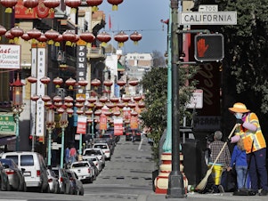 caption: In this Jan. 31, 2020, file photo, a masked worker cleans a street in the Chinatown district in San Francisco. Police and volunteers have increased their street presence after a series of violent attacks against older Asian residents in Bay Area cities stoked fear and subdued the celebratory mood leading up to the Lunar New Year. (AP Photo/Ben Margot, File)