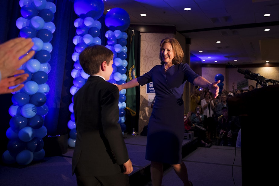 caption: 8th District candidate Kim Schrier celebrates on stage with her son, Sam, on Tuesday, November 6, 2018, at the Hilton in Bellevue.