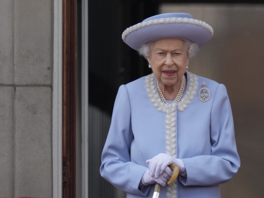 caption: Queen Elizabeth II walks on the balcony of Buckingham Palace in London on June 2, 2022, the first of four days of celebrations to mark the Platinum Jubilee.