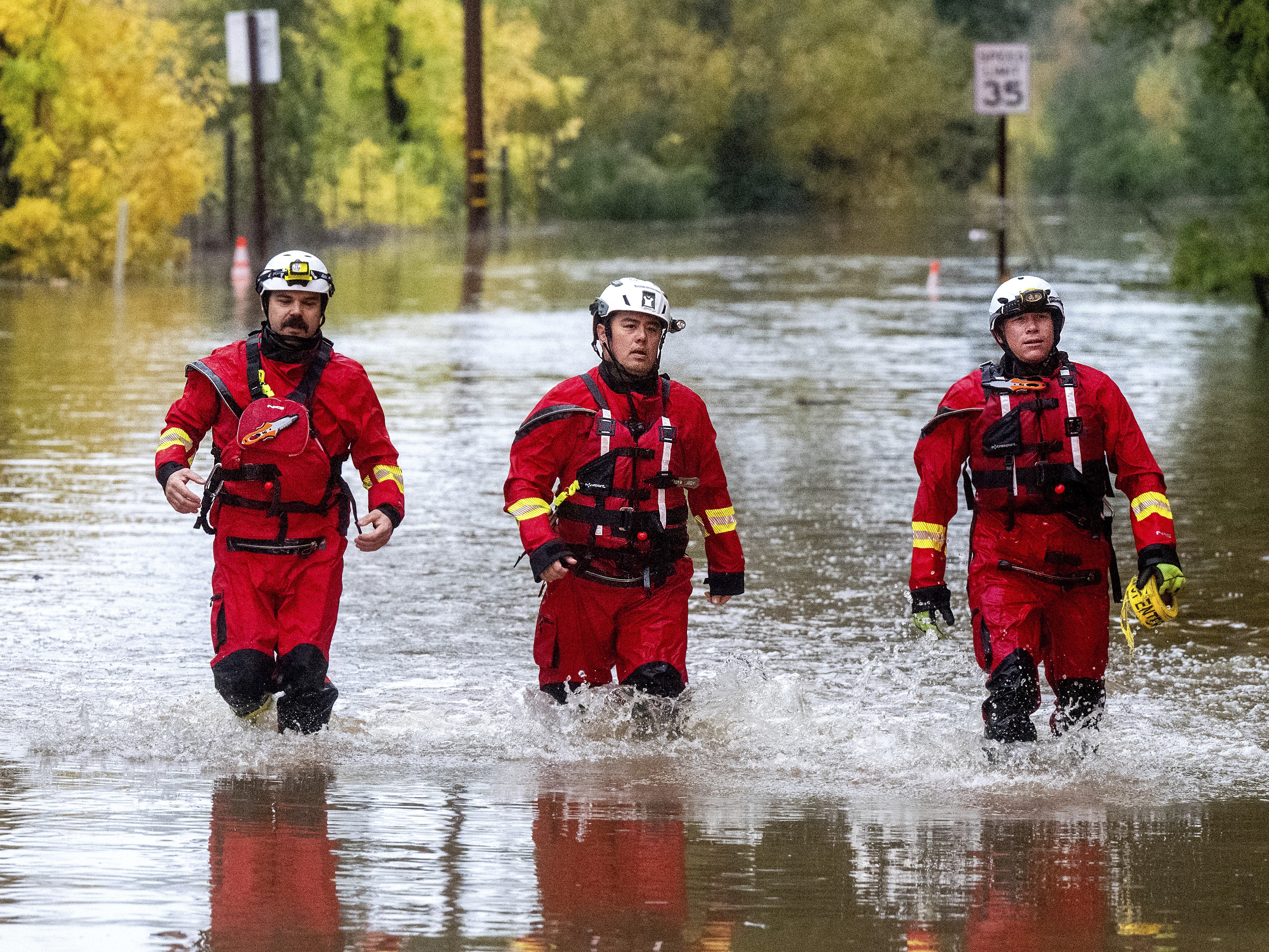 caption: Firefighters walk through floodwaters while responding to a rescue call in unincorporated Sonoma County, Calif., on Friday, Nov. 22, 2024.
