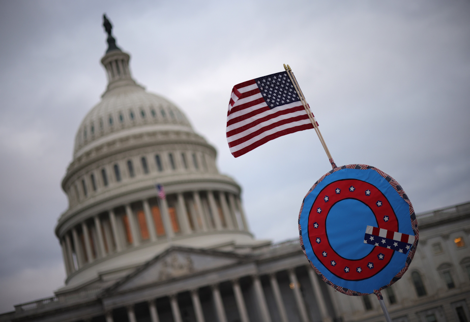 caption: Supporters of former President Trump fly a U.S. flag with a symbol from the group QAnon as they gather outside the U.S. Capitol Jan. 06, 2021 in Washington, D.C. (Win McNamee/Getty Images)