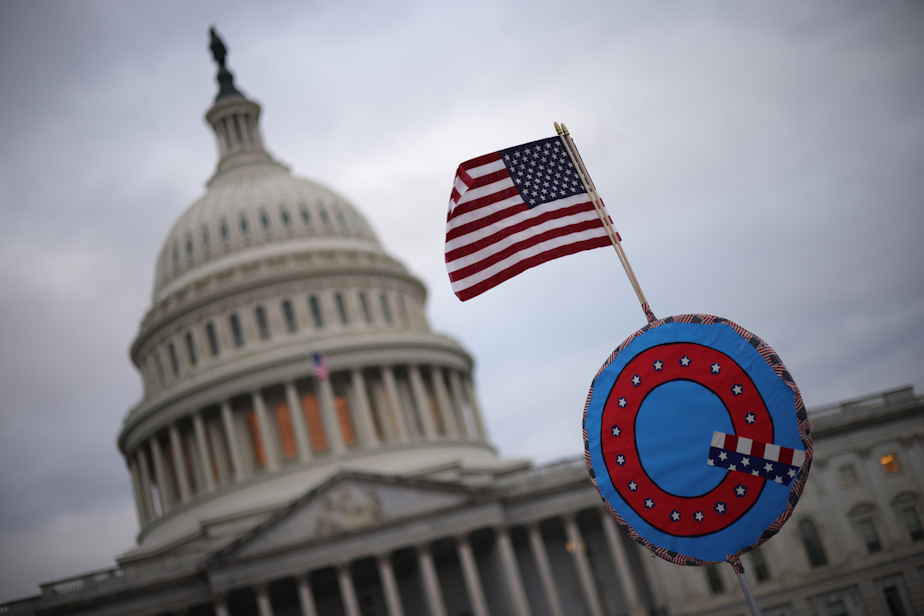 caption: Supporters of former President Trump fly a U.S. flag with a symbol from the group QAnon as they gather outside the U.S. Capitol Jan. 06, 2021 in Washington, D.C. (Win McNamee/Getty Images)