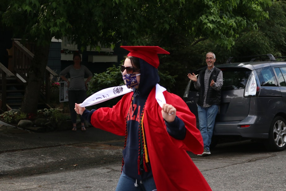 caption: Lydia Urrutia, a fellow Ballard graduate, struts her stuff while a neighbor in the background claps her on.