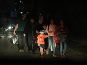 caption: A Palestinian family evacuates their home in the middle of the night during the Israeli bombardment of Gaza.