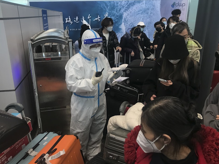 caption: Inbound travelers wait for hours to board buses to leave for quarantine hotels and facilities from Guangzhou Baiyun Airport in southern China's Guangdong province on Dec. 25.