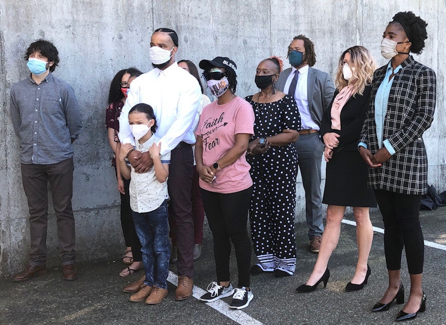 caption: Demonstrators, along with their attorneys and relatives, speak out against the Seattle Police Department's crowd control tactics against protesters during a press conference on Monday, June 22, 2020 in Bellevue. The boy, in front, encountered tear gas during a protest. The woman in the pink shirt is Nikita Tarver, who was hit in the eye with a rubber bullet, and may have lost sight in that eye.