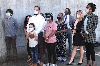 caption: Demonstrators, along with their attorneys and relatives, speak out against the Seattle Police Department's crowd control tactics against protesters during a press conference on Monday, June 22, 2020 in Bellevue. The boy, in front, encountered tear gas during a protest. The woman in the pink shirt is Nikita Tarver, who was hit in the eye with a rubber bullet, and may have lost sight in that eye.
