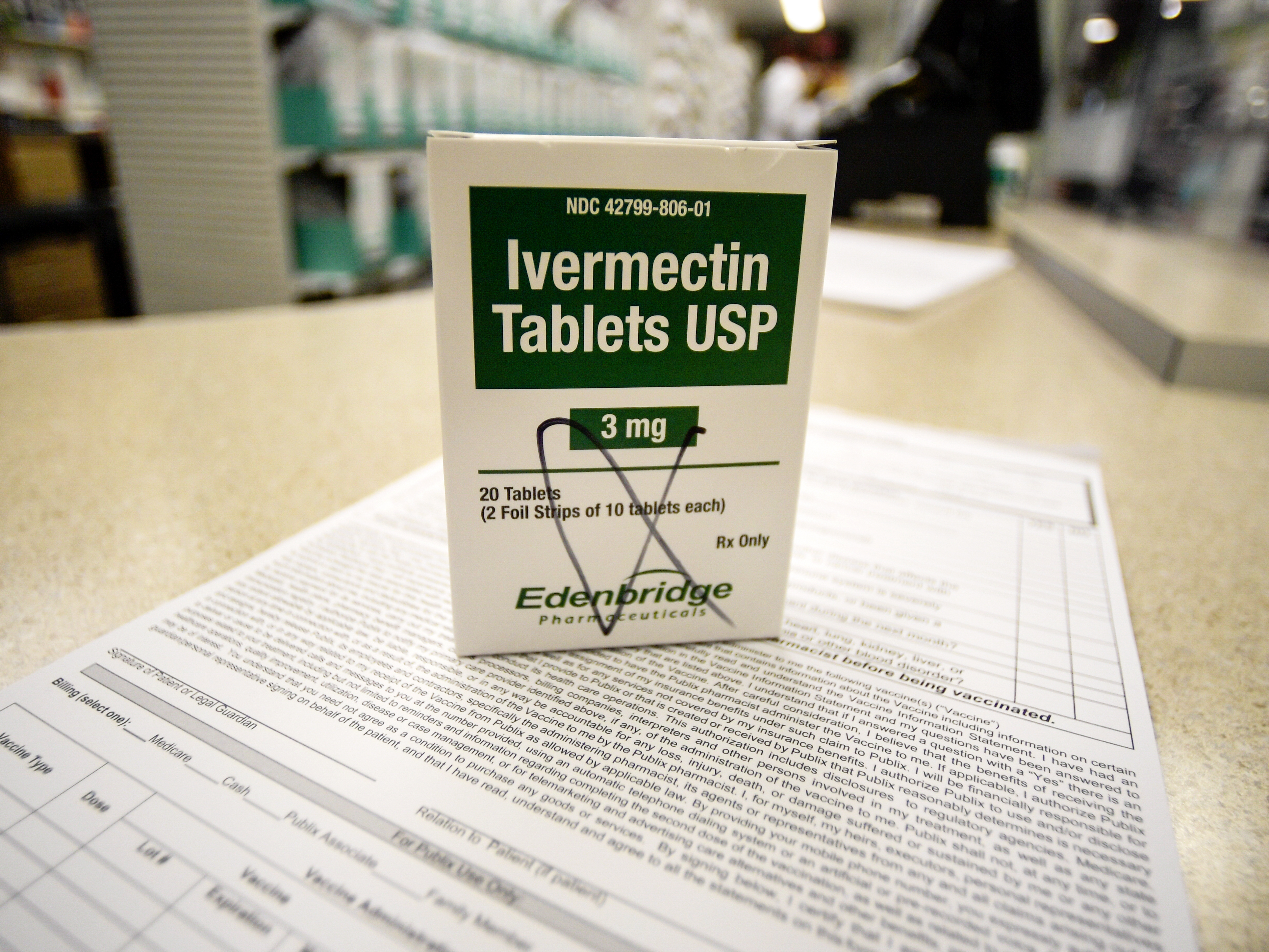 caption: A box of ivermectin is shown in a pharmacy as pharmacists work in the background last year in Georgia.